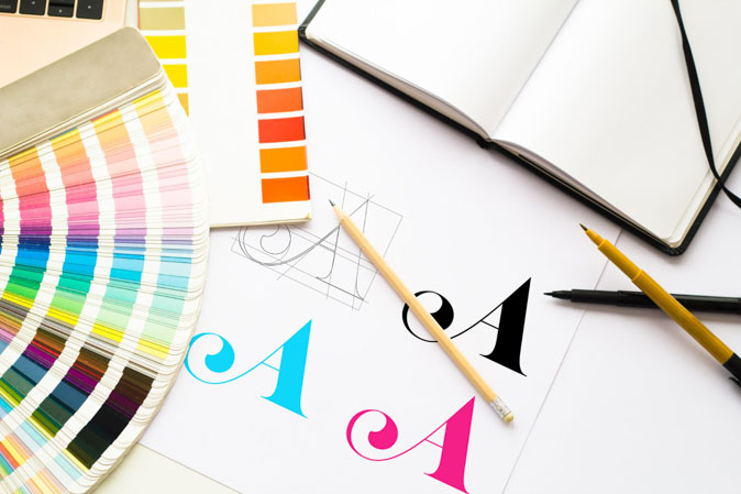 Σχεδιασμός λογοτύπου με τέσσερις διαφορετικές χρωματικές εκδοχές του γράμματος Α να απεικονίζονται σε χαρτί.