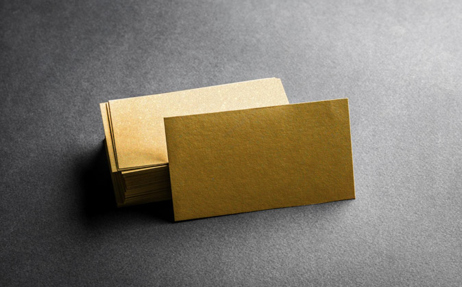 Δείγματα από χρυσές επαγγελματικές κάρτες στοιβαγμένες η μία πάνω στην άλλη σε μαύρο φόντο.