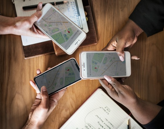 Τρία άτομα κρατούν κινητά έχοντας ανοίξει την εφαρμογή του Google Maps.